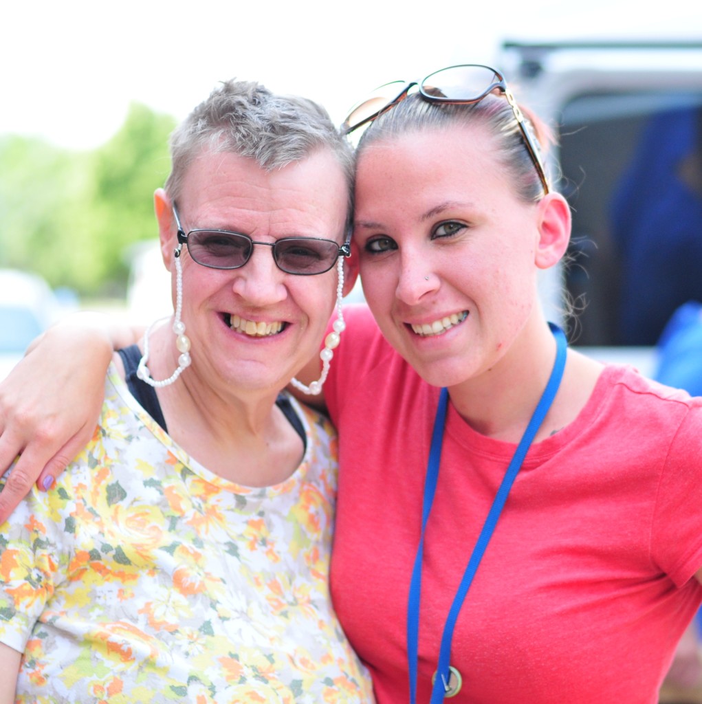 Continuum of Colorado woman and provider smiling in a red shirt with her arm around a smiling older woman in sunglasses