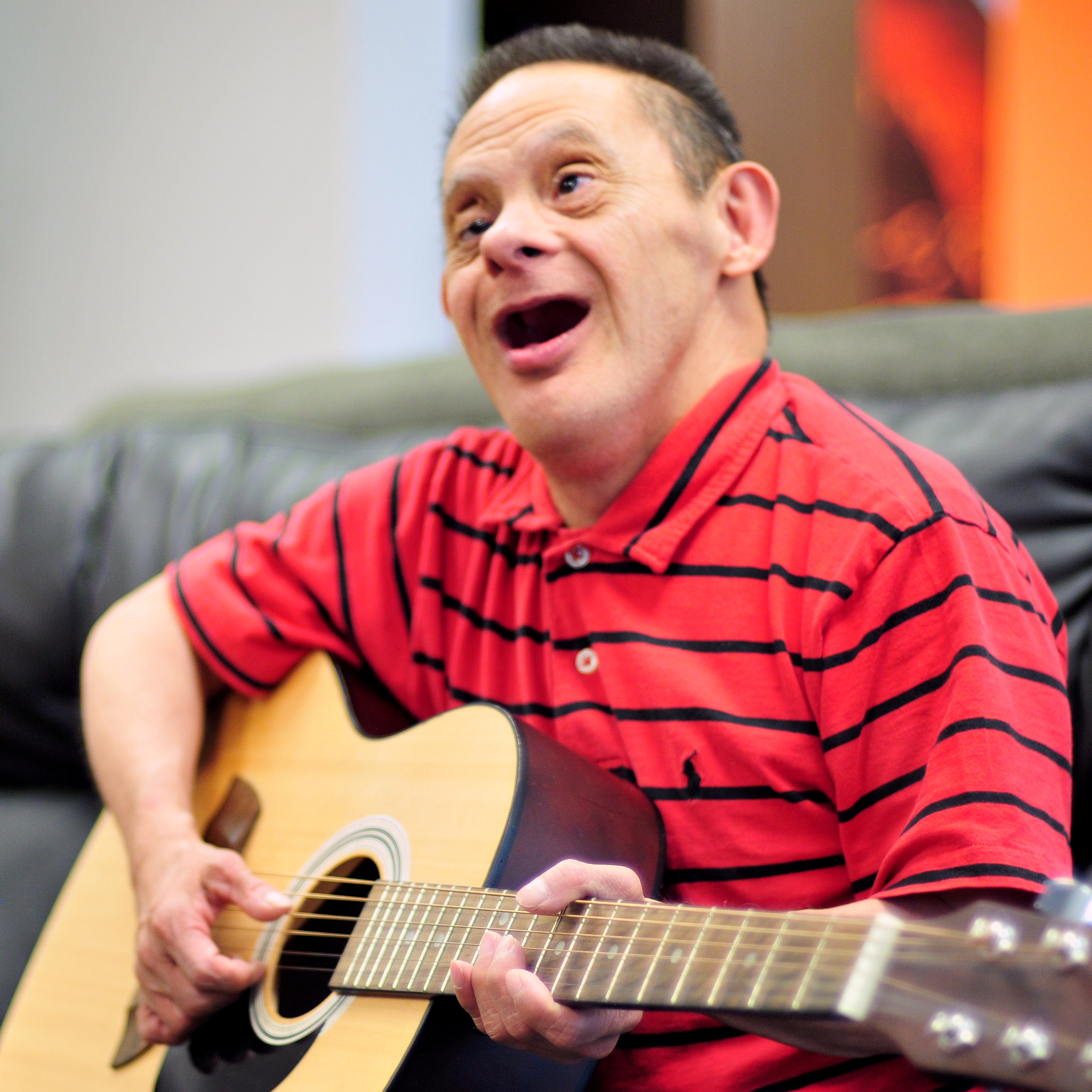 Man playing guitar Man in red striped shirt playing guitar and singin