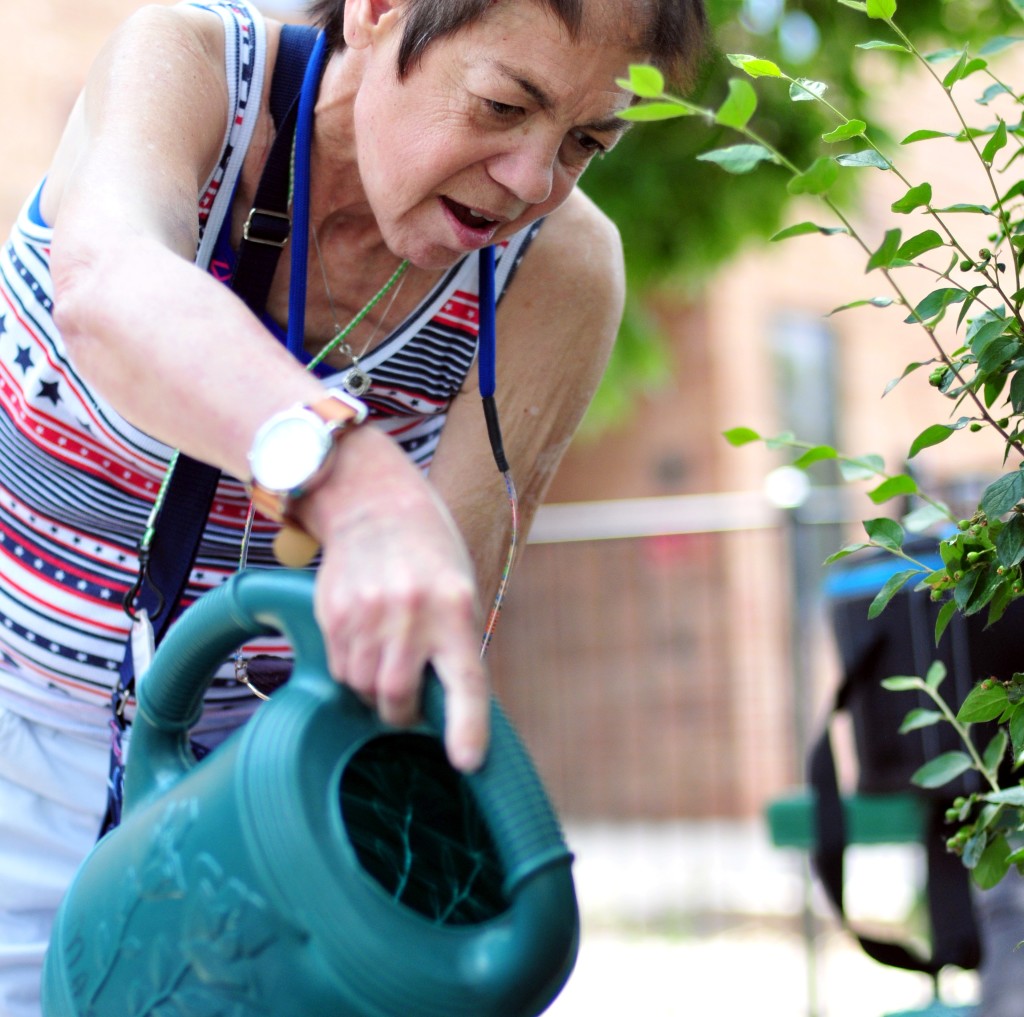 Older woman watering plants with a pitcher