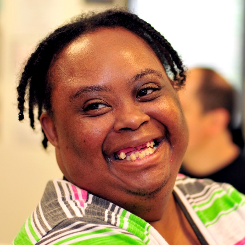 Black woman with black braided hair with a big smile in a striped shirt