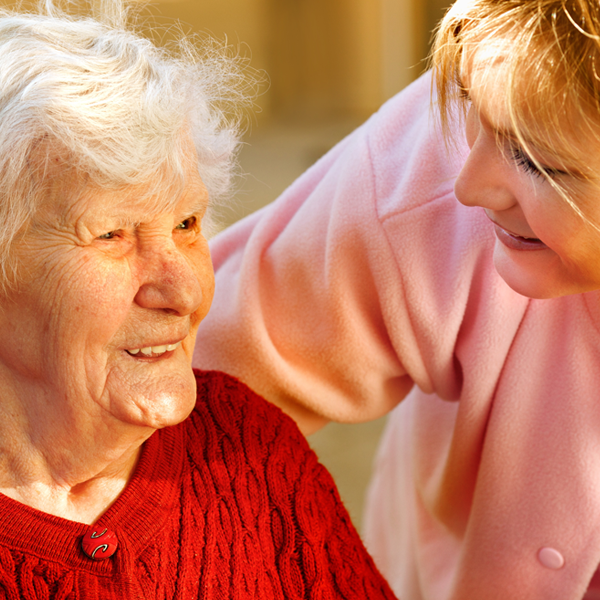 CoC Caregiver with arm around older woman grinning showing support