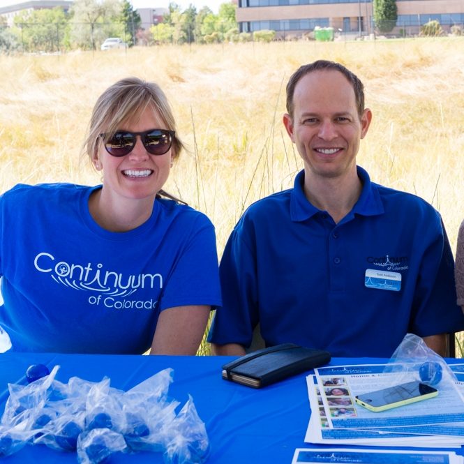 Continuum Staff in Continuum tshirt sitting next to man in collared shirt