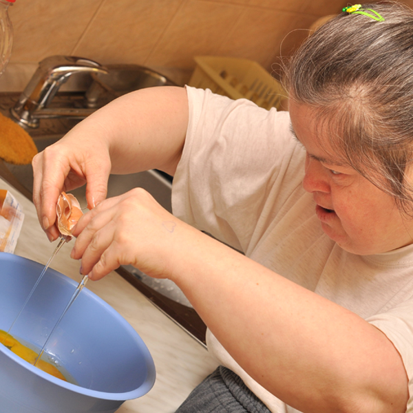 Woman cracking an egg over a blue bowl