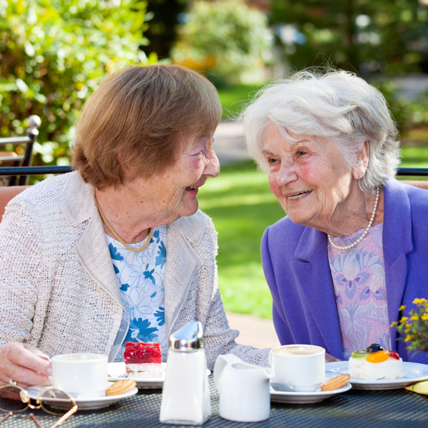 2 older women smiling having a conversation over lunch