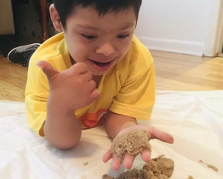 Happy boy playing on the floor with sand