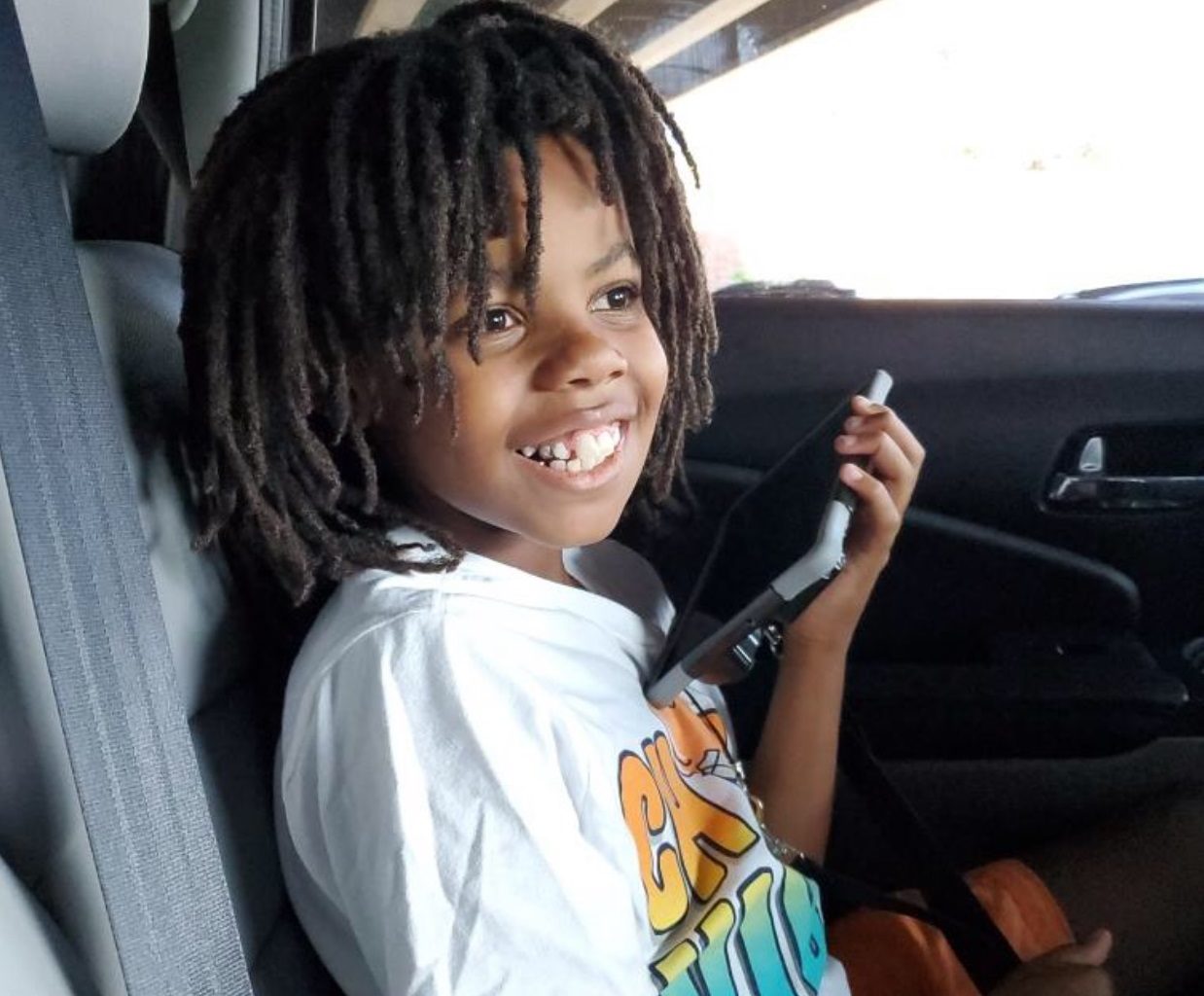 boy smiling using a device in a car