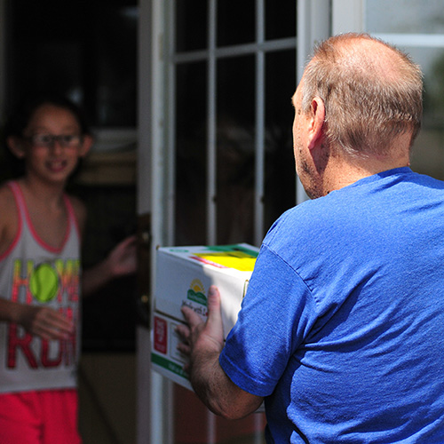 Man delivering a box to a girl at the door